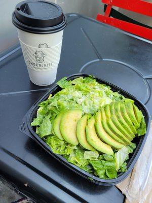 Coffee and custom ordered Caesar Salad without croutons light dressing and avocado on top at outdoor dining