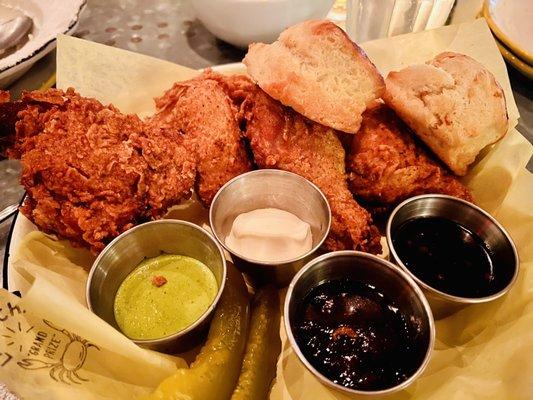 Half fried chicken with biscuits, pickles, green harissa, oyster aioli, and jams