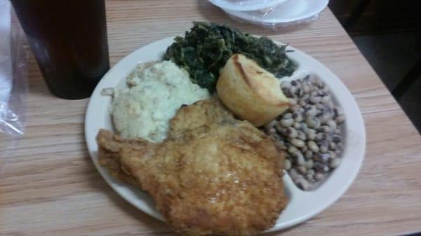 Fried pork chop, dressing with gravy, greens, black eyed peas, and cornbread muffin.