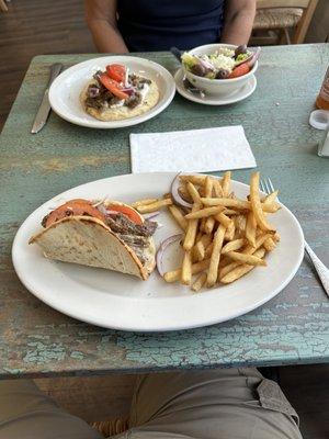 Steak Pita Sandwiches (open in the background, closed with a bite out (sorry) in the foreground.  You can see the Greek Salad and fries