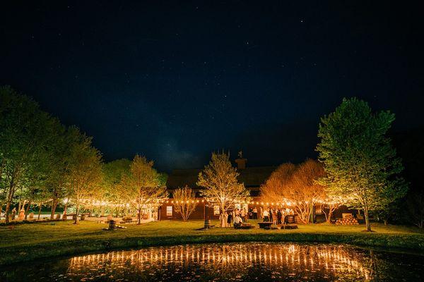 An evening shot at McGuire's Millrace Farm featuring the ambient lighting, pond, firepit and outdoor bar.  Photo by Scott Henry Photography