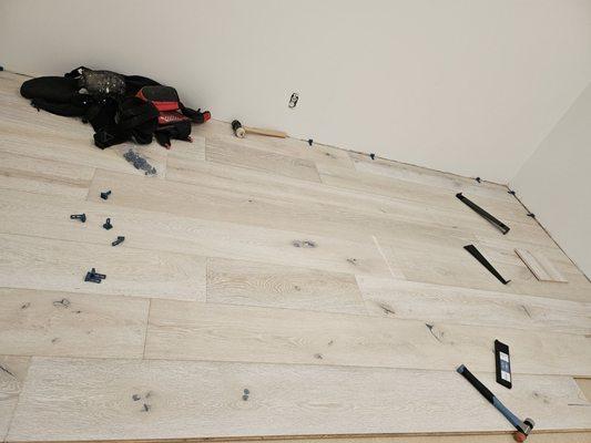 Install of underlayment and engineerd white washed wood flooring.