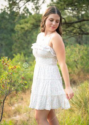 Senior girl, floral short dress in the field outdoors