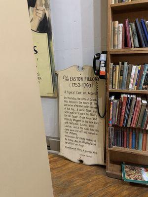 History sign and bookcase inside main entrance heading to the back and towards the bathroom