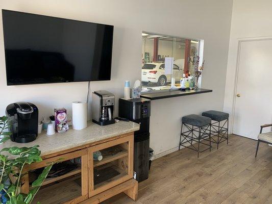 Cool waiting room with a flat screen tv, Kureig coffee machine and hot/cold water dispenser.