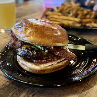 Avocado bacon burger with added tomatoes. Thick, juicy patty, nicely seasoned, generous serving of sliced avocado, Brioche bun.