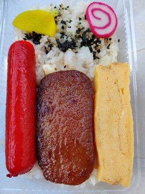 $3.99 bento includes hotdog, spam, tamagoyaki, fishcake, furikake, and takuan on a bed of white rice