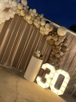 Light-up numbers, beige draping and white cylinder cake stands