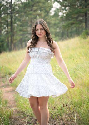 Senior girl, floral short dress in the field with a twirl outdoors