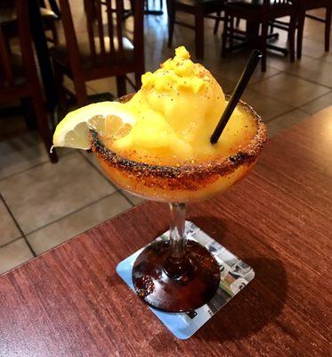 Mango Margarita garnished with Fresh Mango & served in a Tajín rimmed glass. Highly Recommended.