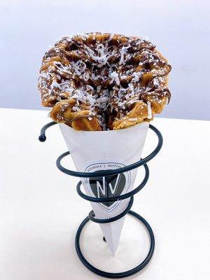 Vanilla Belgian Waffle in a cone with nutella drizzle, coconut flakes and powdered sugar.