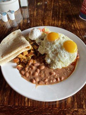 Red beef enchilada with eggs, beans and potatoes.