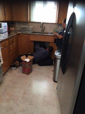 Tim removing the old garbage disposal being assisted by his wife