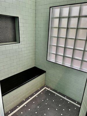 Detail of walk in shower, floor, glass brick window, bench and shampoo niche