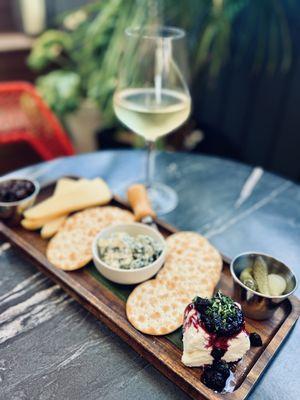 Cheese board with crackers, jam, and cornichons