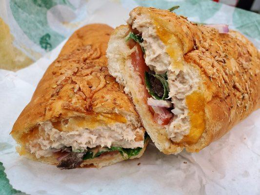 Tuna on cheddar herb bread with onions,  tomatoes,  spinach,  chipotle southwest sauce and some vinegar