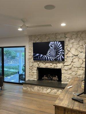 65" frame TV over stone fireplace