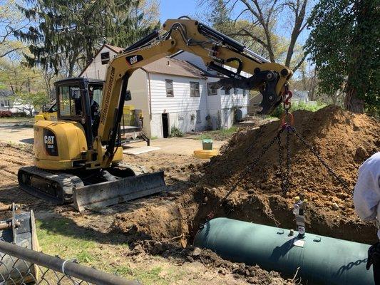 Excavator installing a new propane tank in the ground