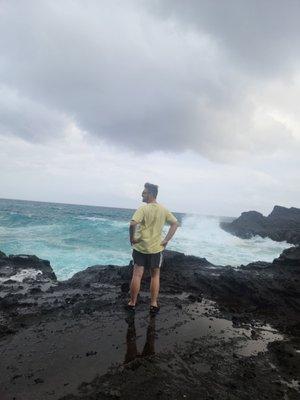 Posing next to the cove with waves crashing