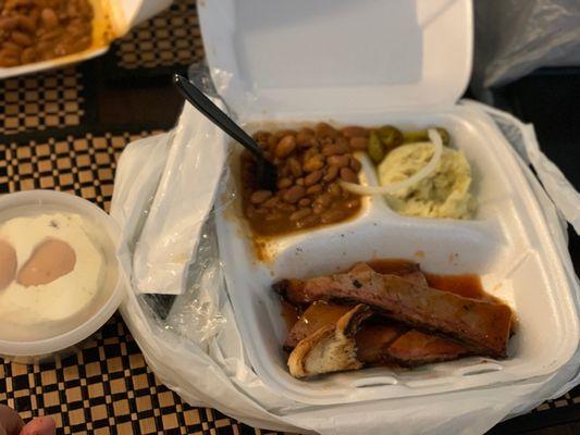 Brisket Plate with slice of toast, potato salad, and baked beans. On the side is banana pudding.