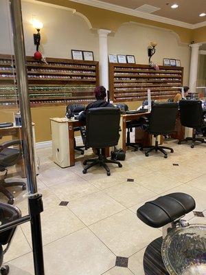 Nail station with protective plexiglass between customer and technician.