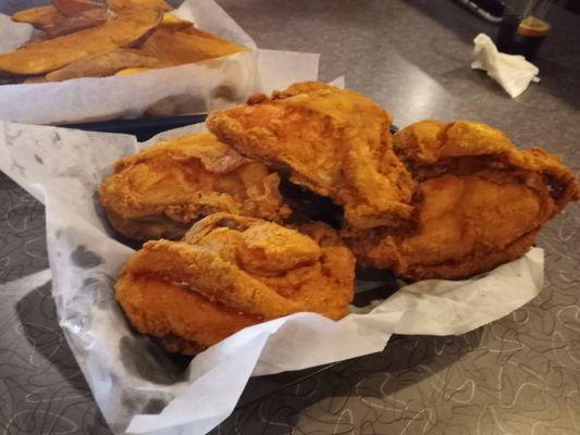 Four pieces of fried chicken breast and their potatoe wedges.