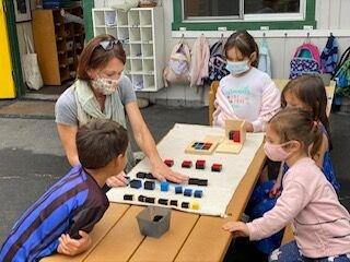 Our Primary Head Teacher giving a lesson with a Montessori material.