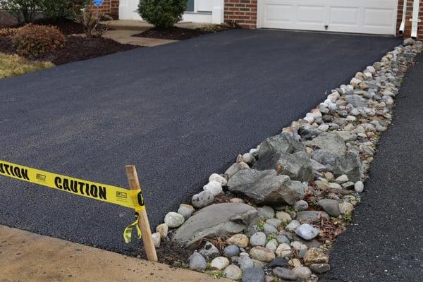 The rocks are the property of the townhouse next door. The paving crew was very precise with their placement of the pavement.