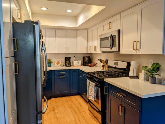 Blue and white shaker cabinets, quartz countertop with blue veining to match, raised recessed lighting, geometric backsplash