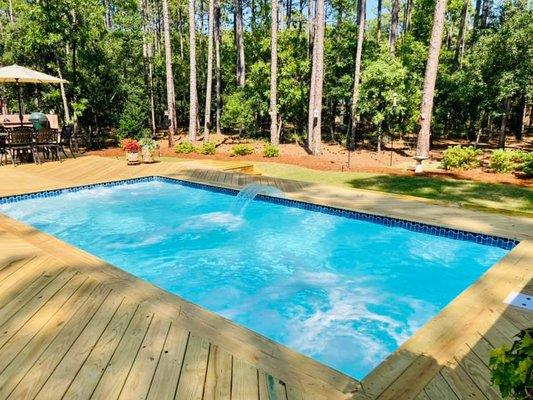 Outdoor pool with water feature and deck.