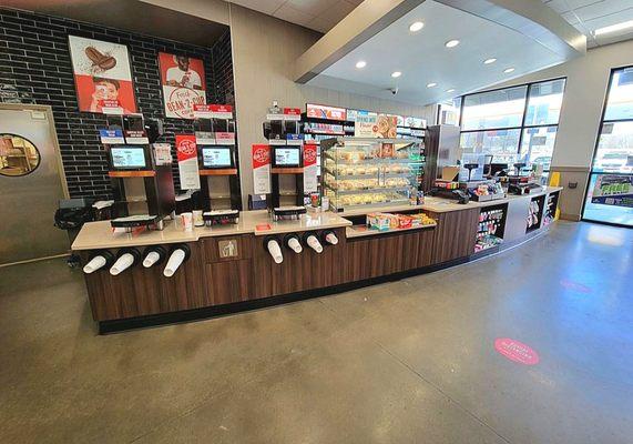 The coffee machines, pastries, and cash register counter.