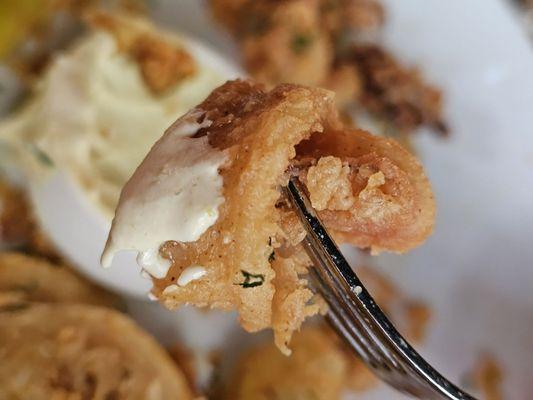 Close-up of a piece of the Fried Calamari appetizer on a fork.