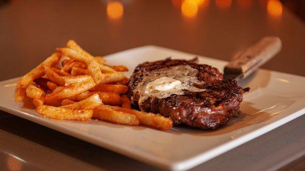 Steak with butter topping, fries, and steak knife at Brew Brothers.