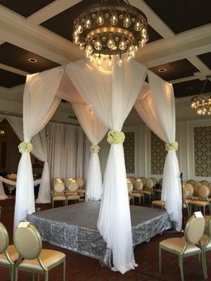 4 Post Pipe and Drapes with Riser , covered with Silver Sequin, and Flowers. Gabro Event Services