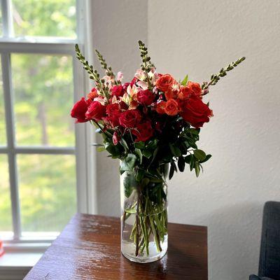 red and orange roses with snap dragon fresh cut flowers in a vase