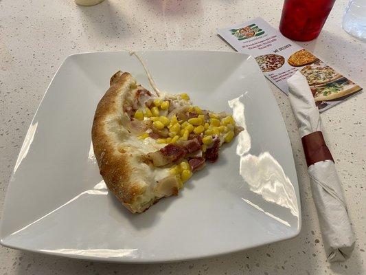 A slice of Corn and Bacon Pizza.