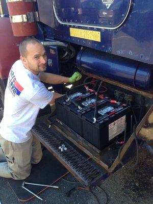 Tim installing a fresh set of batteries in a Tri-Axle dump truck.