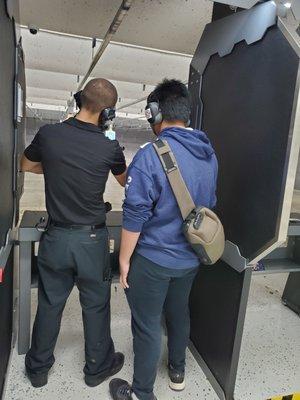 Employee teaching how to handle a gun to a first timer.