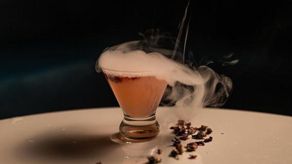 Gimmie Bezos - Ketel One, Orange Liqueur, Raspberry Jam, Rose Syrup, Lemon, Rose Buds, Topped with Champagne, Citrus Smoke Bubble