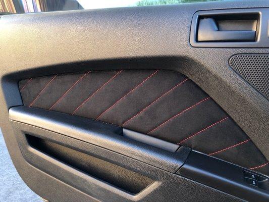 Door panel insert in black suede with red stitching.