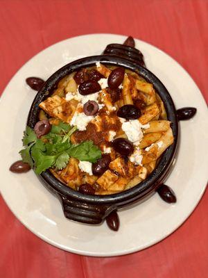 Penne pasta with chicken, olives and feta cheese on top.