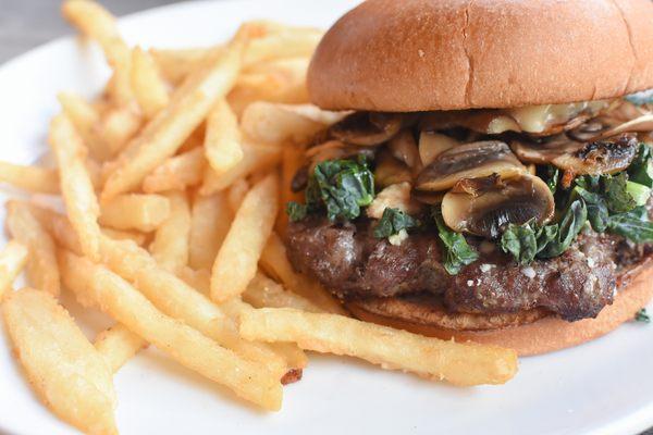 Bison burger with sautéed mushrooms, bleu cheese, black garlic mayo, and arugula on a brioche bun.