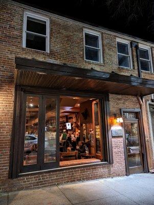 Outside. Storefront at night. Low key. The Crunkleton is located between Tropical Smoothie Cafe (The Book Shop) and Tea Hill (Cha House).