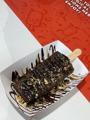 Cookies and cream paleta dipped in milk chocolate drizzled with dark chocolate/caramel and covered with peanuts.