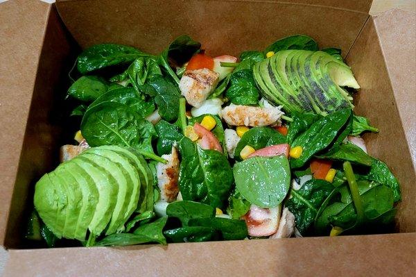 Grilled chicken with spinach, corn, tomatoes, cucumbers, with avocado topping.