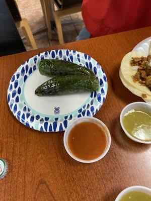 A couple of charred jalapeños and their salsa