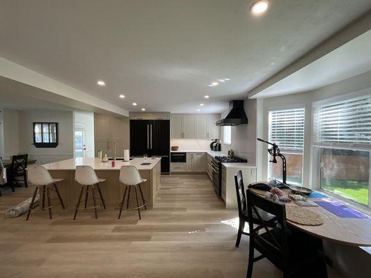 An open kitchen concept layout with kitchen counter seating, new appliances, flooring, and kitchen cabinets.