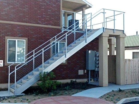 pre-cast concrete stair case with 1/8" stainless steel cable railing @ 3" center to center, finish brushed, fascia  mounted.s...