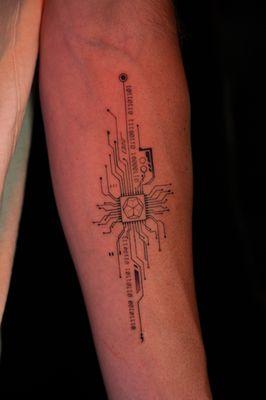 Custom single needle memorial tattoo incorporating a computer chip symbolizing endurance and connection alongside their names in binary code