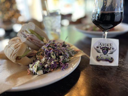 Turkey Bam Brie Lam and Fig Jam sandwich with a side of kale slaw and a glass of Chronic Cellars Purple Paradise.